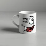 A white ceramic coffee mug featuring a bold, cartoon-style winking face with a wide, mischievous grin, a single visible tooth, and one large expressive eye, set against a neutral grey studio background.