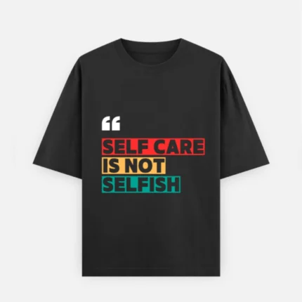 Front view of a premium black unisex oversized heavyweight t-shirt. The chest displays white quotation marks above the bold graphic statement "SELF CARE IS NOT SELFISH", with "SELF CARE" on a red background block, "IS NOT" on a yellow block, and "SELFISH" on a teal block. Features a loose crew neckline and relaxed slouchy sleeves.