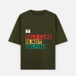 Front view of a unisex olive green oversized t-shirt made of 240 GSM heavy 100% cotton fabric. The chest features a graphic design starting with white quotation marks, followed by the text "SELF CARE IS NOT SELFISH" in bold capital letters. Each line is enclosed in a colored rectangular block: "SELF CARE" in red, "IS NOT" in light yellow, and "SELFISH" in teal blue. The shirt shows a relaxed crew neck, dropped shoulders, and a stylishly long, slouchy drape.