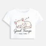 White crop top featuring a cute cartoon illustration of a sleeping kitten with the text "Good Things Take Time."